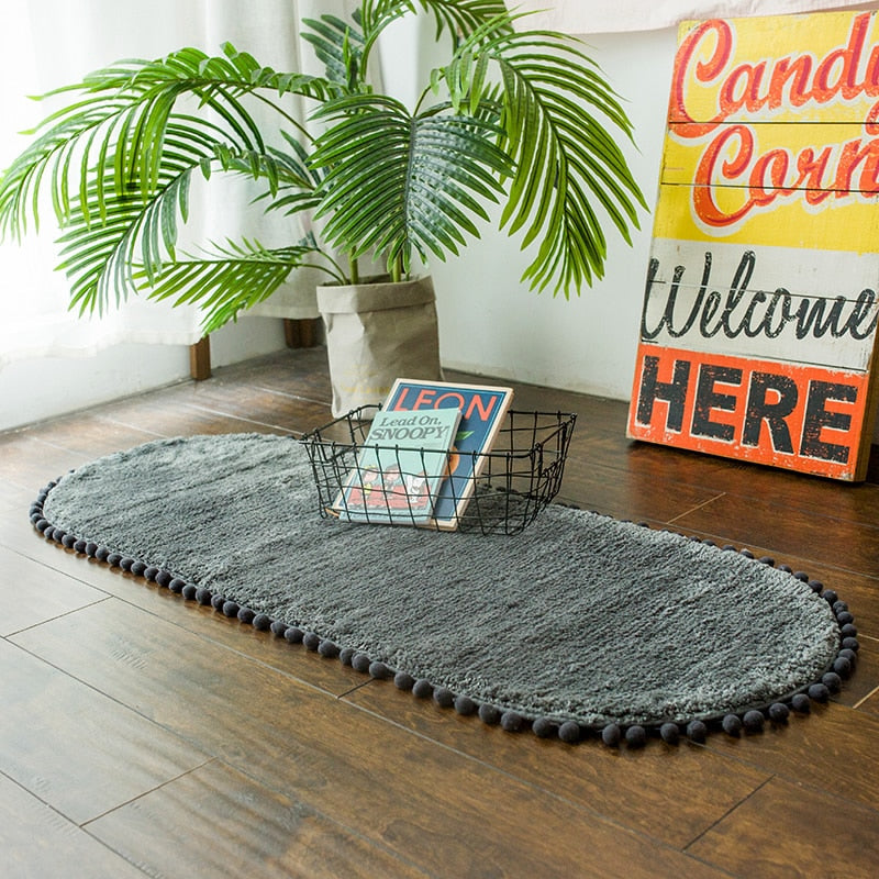 Tapis ovale antidérapant orné de pompons